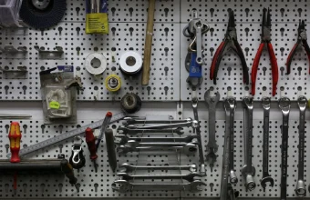 A wall-mounted pegboard with wrenches, pliers, and hand tools neatly organized in rows