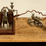 Antique Western Electric telegraph key and sounder from 1876, displayed on a wooden museum base