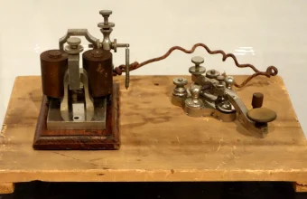 Antique Western Electric telegraph key and sounder from 1876, displayed on a wooden museum base