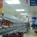 Empty bread shelves in a UK supermarket aisle, illustrating a food supply chain disruption