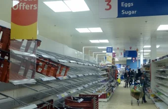 Empty bread shelves in a UK supermarket aisle, illustrating a food supply chain disruption