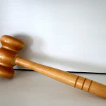 A wooden gavel resting on a plain light background, representing a verdict reached by a panel rather than a single decision-maker