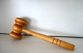 A wooden gavel resting on a plain light background, representing a verdict reached by a panel rather than a single decision-maker