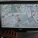 A windshield-mounted GPS navigation device showing a live map with a location marker, illustrating real-time location tracking