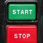 A green Start button and red Stop button on an industrial control panel, representing a workload that spins up on demand and shuts off when idle