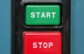 A green Start button and red Stop button on an industrial control panel, representing a workload that spins up on demand and shuts off when idle