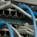 Two enterprise network switches with CAT5 Ethernet cables plugged into their ports