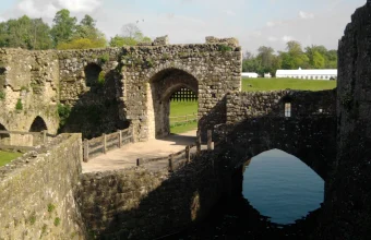 Leeds Castle's medieval moat, portcullis gate, and stone bridge reflected in the water