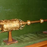 A gold ceremonial mace of office displayed in a glass case, a physical symbol that only one officeholder can possess at a time