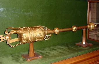 A gold ceremonial mace of office displayed in a glass case, a physical symbol that only one officeholder can possess at a time