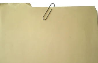 A manila file folder with a paperclip clipped to its tab, against a white background