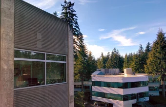 A Microsoft campus building in Redmond, Washington, showing its glass-walled exterior surrounded by evergreen trees