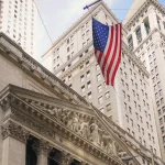 The New York Stock Exchange building facade with a large American flag, where Nscale plans to list its shares