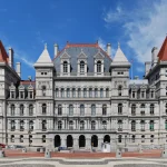 The New York State Capitol building in Albany, New York, photographed from the Empire State Plaza under a clear blue sky