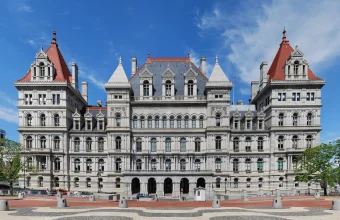 The New York State Capitol building in Albany, New York, photographed from the Empire State Plaza under a clear blue sky