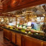 An elaborate all-you-can-eat buffet counter with ornate brass fixtures and small bowls of food arranged along a glass display case