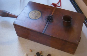 An antique 1814 wooden ballot box with voting balls and a small measuring cup on top, a literal visual metaphor for two-phase commit's voting phase