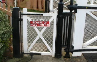 A small wicket gate built into a much larger railway level-crossing gate, providing a pedestrian path beside the main barrier
