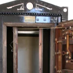 An antique bank vault door swung wide open, exposing its intricate mechanical locking bolts and the empty interior beyond