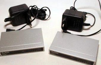 Two Zyxel network switches with power adapters on a white background