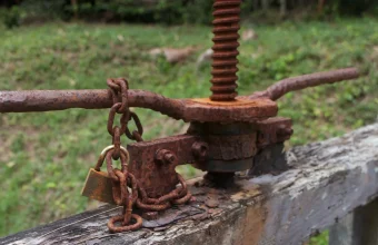Rusted sluice gate winch with a padlock and chain wrapped around its handle