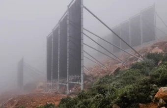 Rows of tall fog-collection nets on a misty hillside, a passive way to harvest water from air