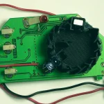 An open smoke sensor showing its green circuit board, black optical detection chamber and battery clip