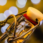 Close-up of a glass swing-top bottle neck with a wire bail and a cream-colored stopper against a blurred amber background, a literal bottleneck