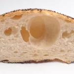 Cross section of a poppy seed bread roll with a large hole in the crumb