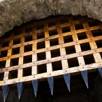 Wooden portcullis with iron spikes raised inside a stone gateway arch at Cahir Castle in Ireland