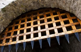 Wooden portcullis with iron spikes raised inside a stone gateway arch at Cahir Castle in Ireland
