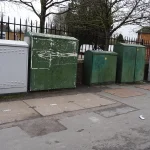 BT’s TalkTalk Rescue Turns Telecom Continuity Into a New Merger-Control Ground A row of green and grey fibre broadband street cabinets on a pavement beside a fence in Iver, England