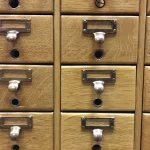 How to Encrypt PII in Python and Keep It Searchable With Blind Indexes Rows of closed oak library card catalog drawers, each with a brass pull and a blank label holder