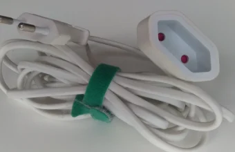 A white extension cord with a Europlug at one end and a socket at the other, coiled and held together by a green strap