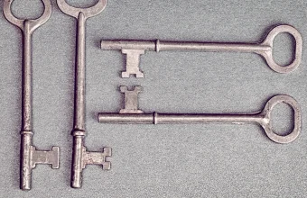 Four antique skeleton keys laid on a gray textured surface