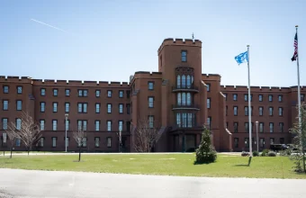Exterior of Building 1 on the Department of Homeland Security’s St. Elizabeths campus in Washington, D.C., a red brick building with a central tower and flagpoles under a blue sky