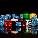 A pile of colorful six-sided and polyhedral dice with reflections on a black glossy surface