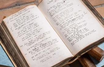Denmark’s oldest church book, from Holmens parish, open on a stack of books; its handwritten pages record births between 1617 and 1639