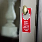 OpenAI’s Shared Training Signal Turns robots.txt Into a Purpose Token From a Same-Day Individual Draft, and a Group That Blocks One Folder Reads as a Preference for Training on Every Other Path Red hotel door hanger reading Do Not Disturb in four languages on a brass doorknob, a request that does not lock the door