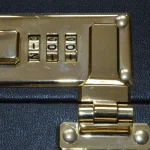Brass three-digit combination lock with its number wheels on a black leather briefcase