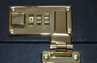 Brass three-digit combination lock with its number wheels on a black leather briefcase