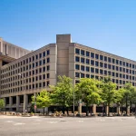 The J. Edgar Hoover Building, FBI headquarters in Washington, D.C., seen from the street under a clear blue sky