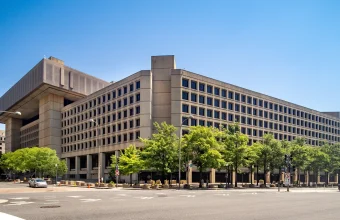 The J. Edgar Hoover Building, FBI headquarters in Washington, D.C., seen from the street under a clear blue sky