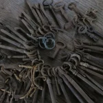 A large collection of old iron keys on key rings spread across a wooden floor