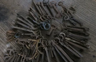 A large collection of old iron keys on key rings spread across a wooden floor