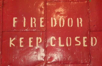 Red steel fire door stenciled FIRE DOOR KEEP CLOSED in cream letters