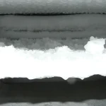Thick frost and ice built up on the shelf and walls inside an opened freezer