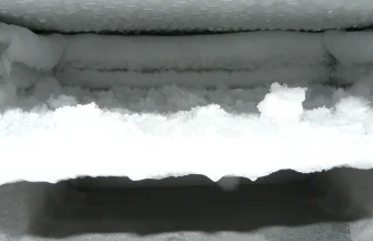 Thick frost and ice built up on the shelf and walls inside an opened freezer