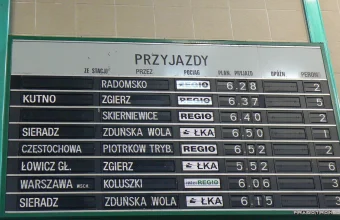 A split-flap arrivals board at Łódź Kaliska railway station in Poland listing trains by time and platform, a picture of a fixed timetable