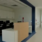An empty hospital ward reception and nursing workstation with computers and a long corridor beyond, at Fiona Stanley Hospital in Perth, Australia